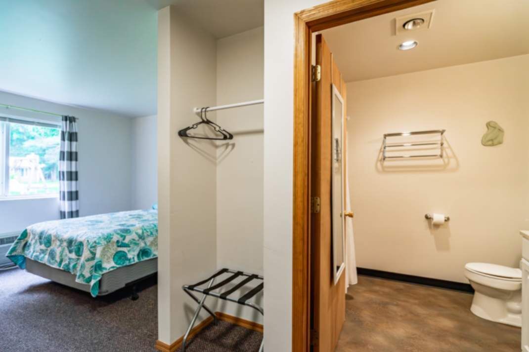 A bedroom with a bed, a window with curtains, and a wall-mounted drying rack.
