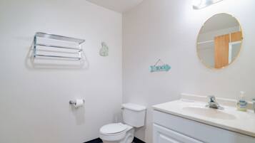 Ein Badezimmer mit Toilette, Waschbecken, Spiegel und Handtuchhalter.