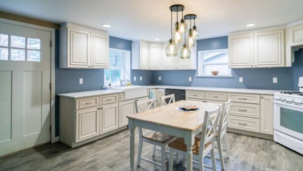 A kitchen with white cabinets, a wooden dining table, and a white stove. - Cabin #7 Wishing Star (Iosco County)
