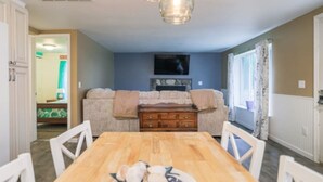 A dining area with a wooden table and chairs, a chandelier, a sofa with a blanket, and a dresser. - Cabin #7 Wishing Star (Iosco County)