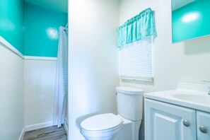 A bathroom with a toilet, a sink, and a shower curtain. - Cabin #4 Wishmaker's Rest (Iosco County)