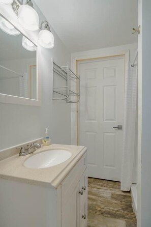 A bathroom with a sink, mirror, and light fixtures. - Cabin #8 Northern Lights (Iosco County)