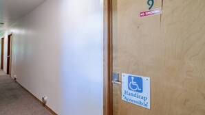 Un passadís amb una porta accessible per a persones amb mobilitat reduïda, un senyalitzador de prohibició de fumar i la porta número 9.