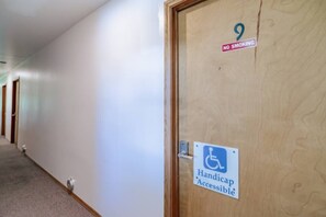 Un pasillo con una puerta accesible para personas con movilidad reducida, un cartel de prohibido fumar y el número 9.