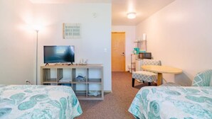 Ein Zimmer mit zwei Betten, einem Fernseher, einem kleinen Tisch und einem Stuhl.