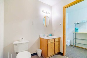 Un baño con inodoro, lavabo, espejo y un pequeño cubo de basura.