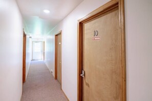 Un pasillo con puertas de madera, una de ellas con el número 10 y un cartel de 'No Fumar'.