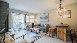 Una sala de estar moderna con chimenea, un sofá, una mesa de centro y un comedor con mesa de madera y bancos.