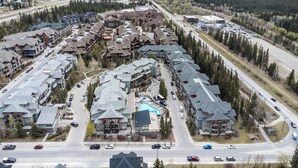 Un resort con varias construcciones, una piscina y una carretera con vehículos.