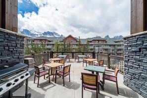 Eine Terrasse mit Sitzgelegenheit und Grill, mit Blick auf ein Gebirge.