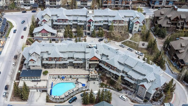 Un hotel de varios pisos con piscina, asientos al aire libre y un telesilla.