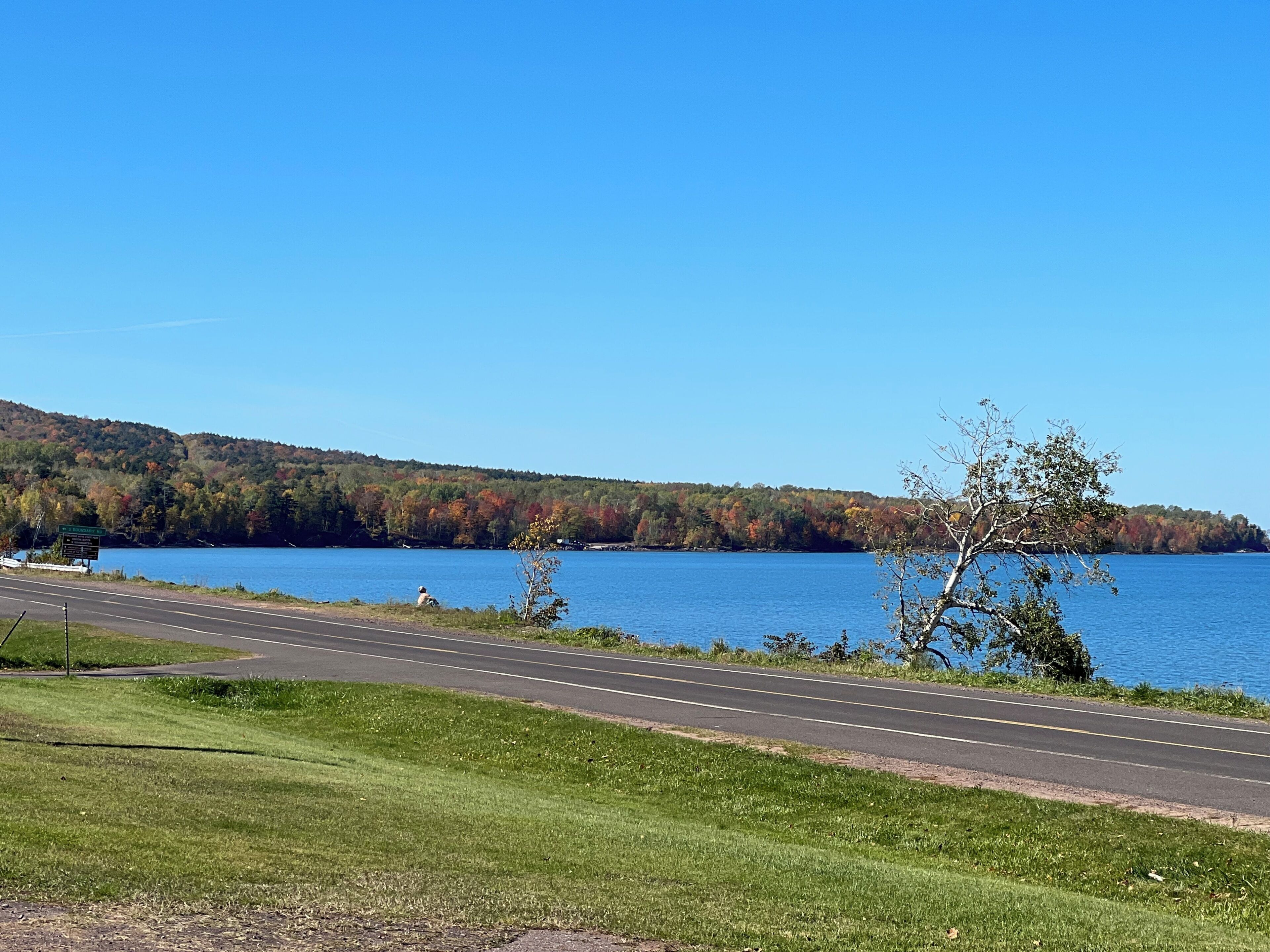 A road leading to a body of water with a hilly backdrop.