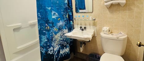 A bathroom with a shower curtain, sink, mirror, and toilet.