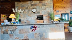 A stone reception desk with a clock, a fireplace, and various decorative items.