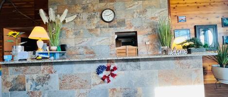 A stone reception desk with a clock, a fireplace, and various decorative items.
