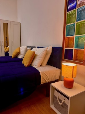 A bedroom with a bed, a nightstand, a lamp, a wardrobe, and a wall with a colorful window. - BBGH Luxury Guest House Close Lisbon (Moita)