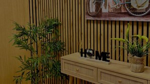 Una habitación con pared de listones de madera, un escritorio de madera con un globo terráqueo y un cartel que dice 'HOME', una planta en maceta y una bicicleta antigua con canasta.