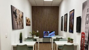 Un salón de conferencias con mesas blancas, sillas verdes y obras de arte enmarcadas en las paredes.
