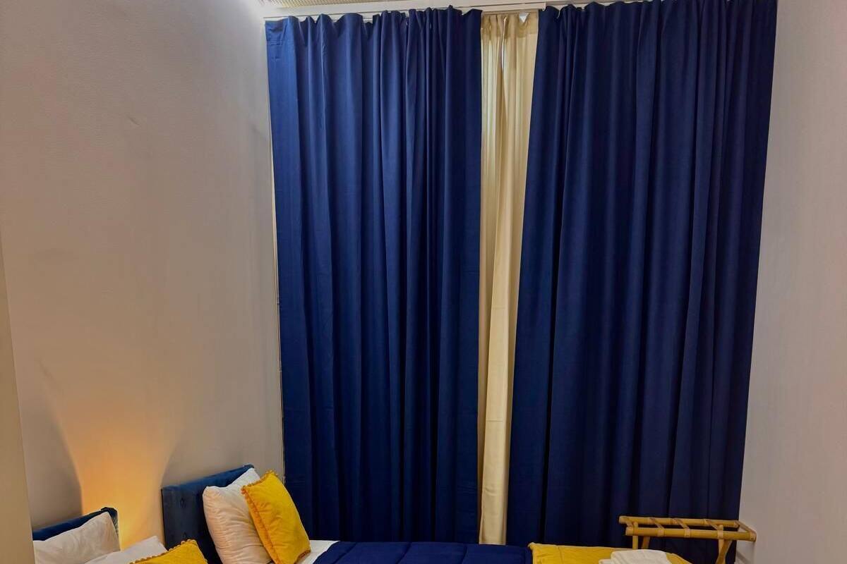A room with two beds, each with a duvet, and a small table with towels.