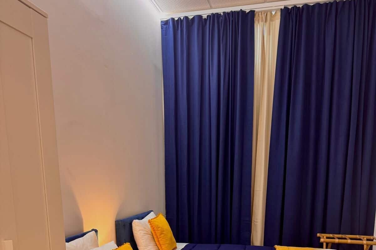 A room with two beds, each with a blue and yellow bedspread, white pillows, and a wooden headboard.