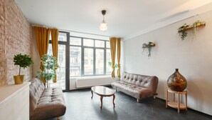 Una sala de estar con dos sofás, una mesa de centro, un candelabro colgante y plantas en macetas.