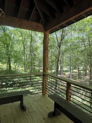 A wooden deck with benches, surrounded by a forested area.
