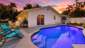 Ein Wohnhaus mit Pool, Gartenmöbeln und einer Terrassenfläche.