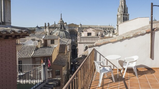 Een terras met witte stoelen, uitzicht op historische gebouwen en een kerktoren.