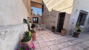 Un pati amb parets de pedra, plantes en testos, una taula i cadires.