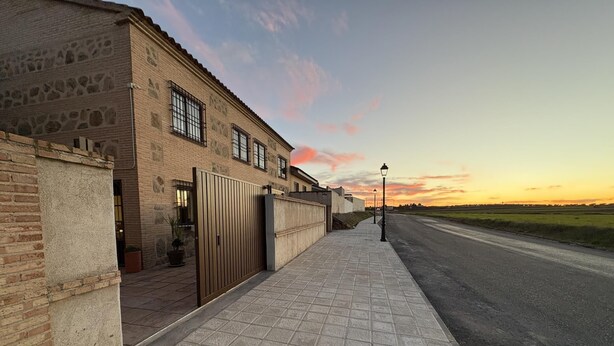 Un edifici residencial amb entrada tancada per reixa, vorada i carretera al fons.