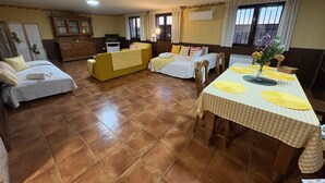 Habitació d'hotel amb dos llits, una taula de menjador amb proteccions de plat de color groc, una televisió i una finestra amb cortines.