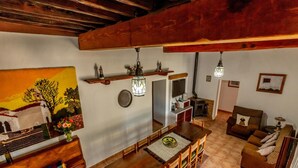 A cozy living room with a wooden dining table, chairs, a sofa, and a fireplace. - Can Pere - 3-bedroom Villa for 7 Guests (Sant Joan de Labritja)
