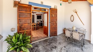 A rustic interior with wooden doors, a dining area, and a ceiling with exposed beams. - Can Pere - 3-bedroom Villa for 7 Guests (Sant Joan de Labritja)