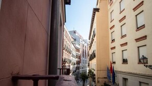 A narrow street with buildings on either side, a bench, and flags. - Collection Gran Vía (Madrid)