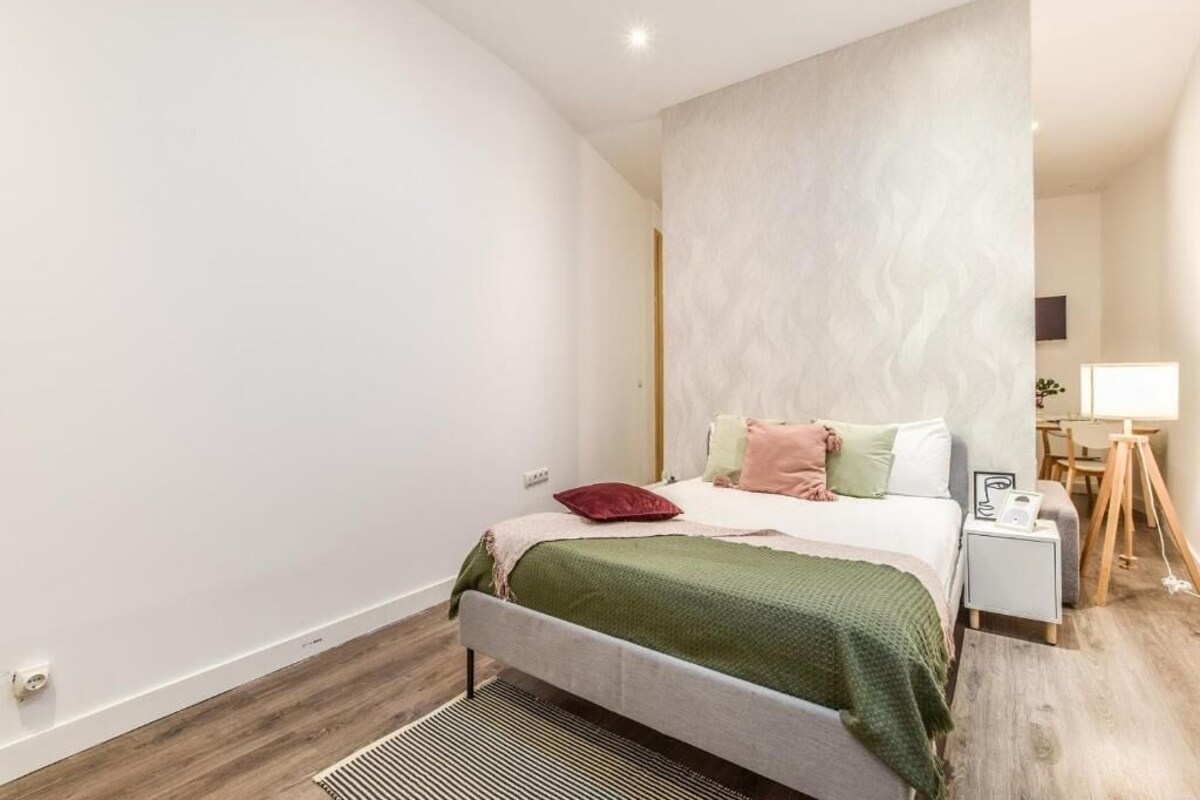 Un dormitorio moderno con cama, mesitas de noche y una lámpara.