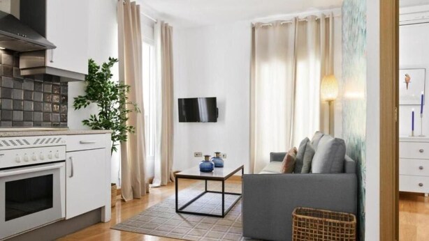 A modern kitchen with a built-in oven and a dining area with a table and chairs. - Collection Gran Vía (Madrid)