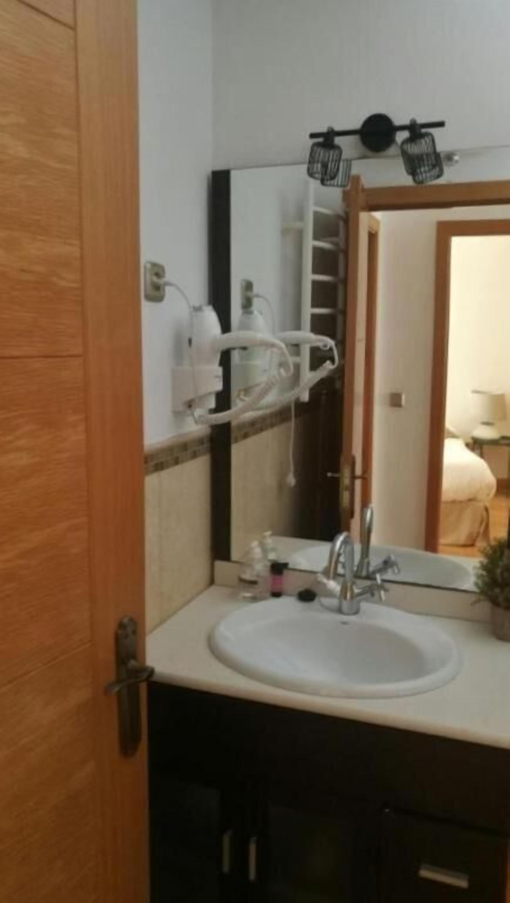 A bathroom with a sink, mirror, towel rack, and a door.