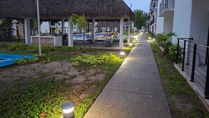 Een resort met een rieten dakgebouw, een zwembad en een verharde looppad.