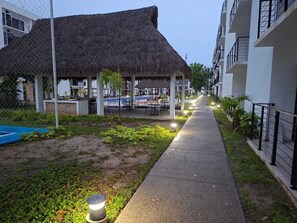 A resort with a thatched-roof structure, a pool, and a paved walkway. - Close to the beautiful beaches of Punta de Mita and 10 minutes from the sea of Bucerias. (Tondoroque)