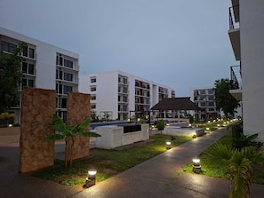 A modern hotel courtyard with a swimming pool, lounge areas, and a stone wall. - Close to the beautiful beaches of Punta de Mita and 10 minutes from the sea of Bucerias. (Tondoroque)