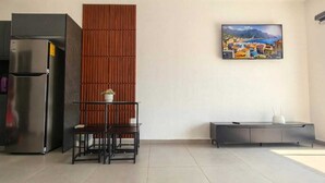 Een moderne keuken met een koelkast, een wand van houten panelen, een eettafel met stoelen en een schilderij van een kustplaatsje.
