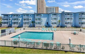 A hotel with a swimming pool, multiple balconies, and a view of a tall building. - Oceanfront Escape Shore Dr Condo Balcony (Myrtle Beach)
