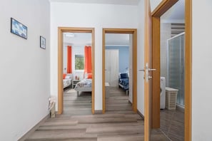 Ein Flur, der zu einem Schlafzimmer mit einem Bett, einem Kleiderschrank und einer Duschkabine führt.