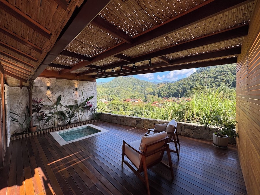 Une terrasse en bois avec un mur en pierre, une piscine et une vue sur un paysage montagneux.