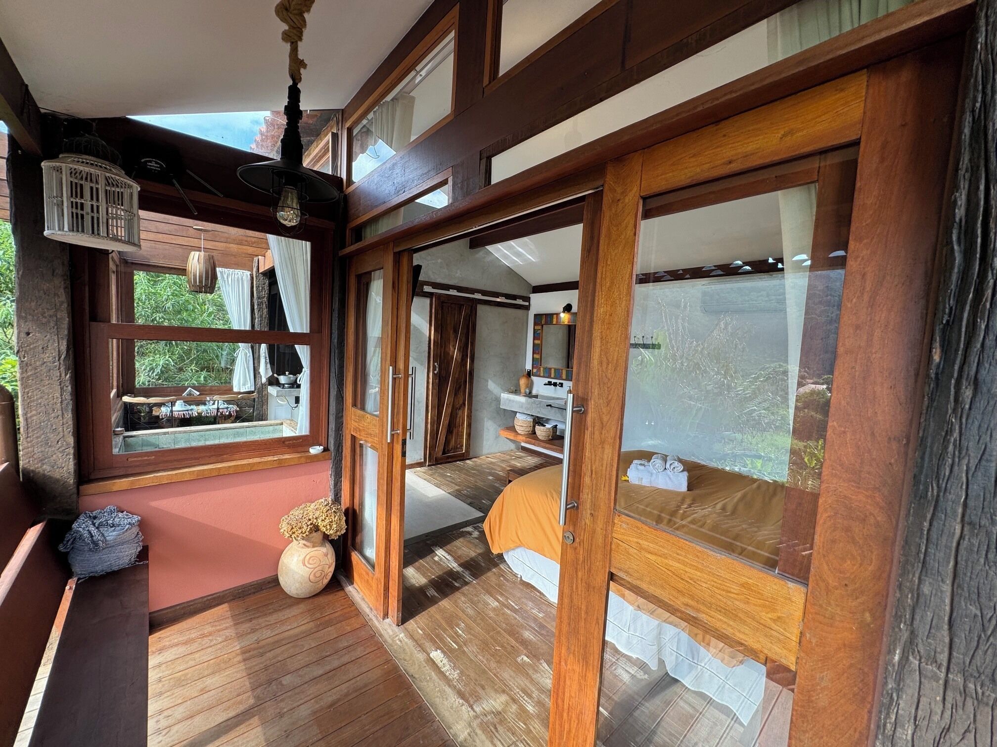 Una habitación con piso de madera, una cama, un ventanal y vistas a zonas verdes.