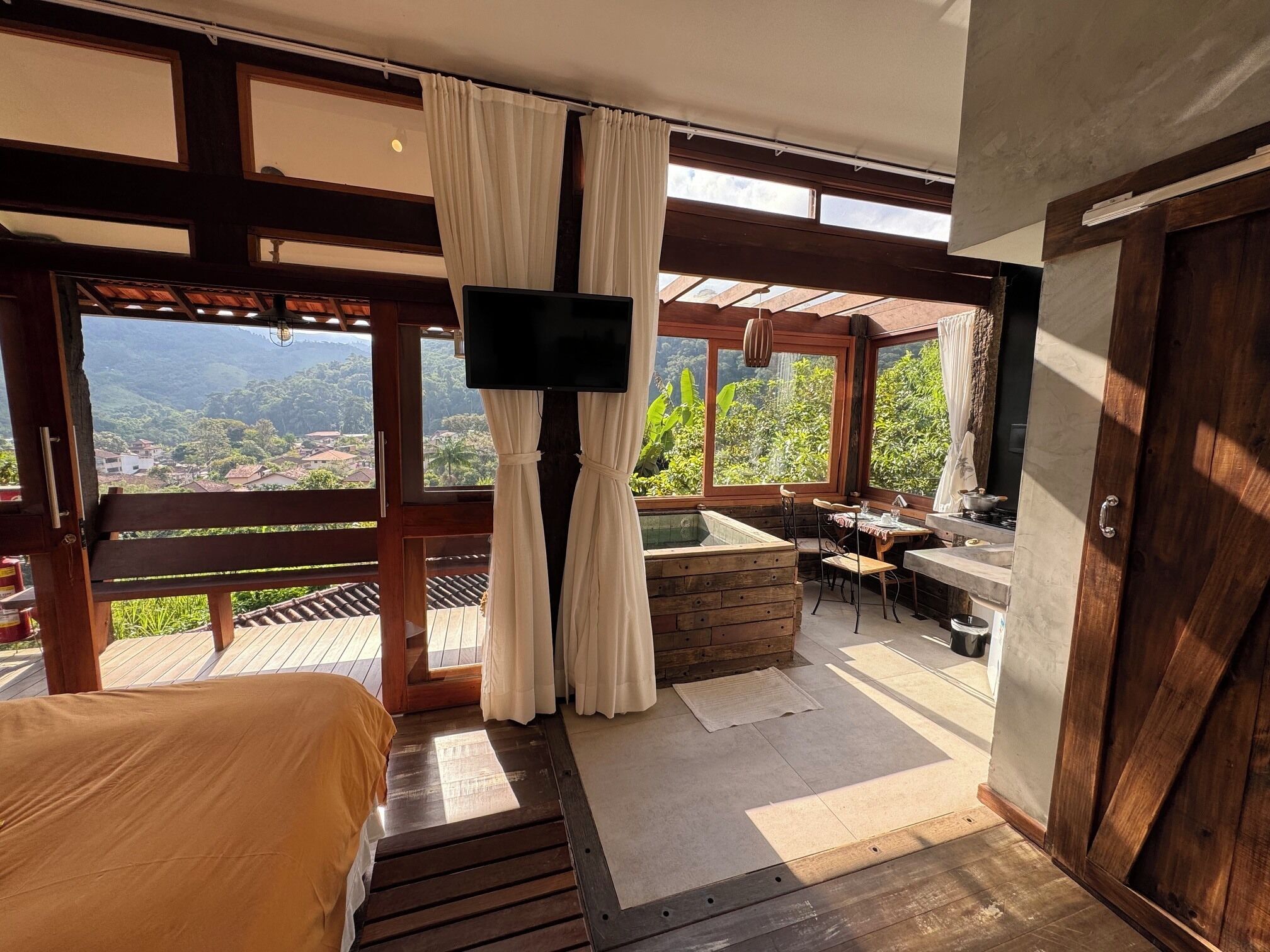 Ein Zimmer mit einem Bett, einem Fernseher, einer Whirlwanne und Blick auf die Berge.