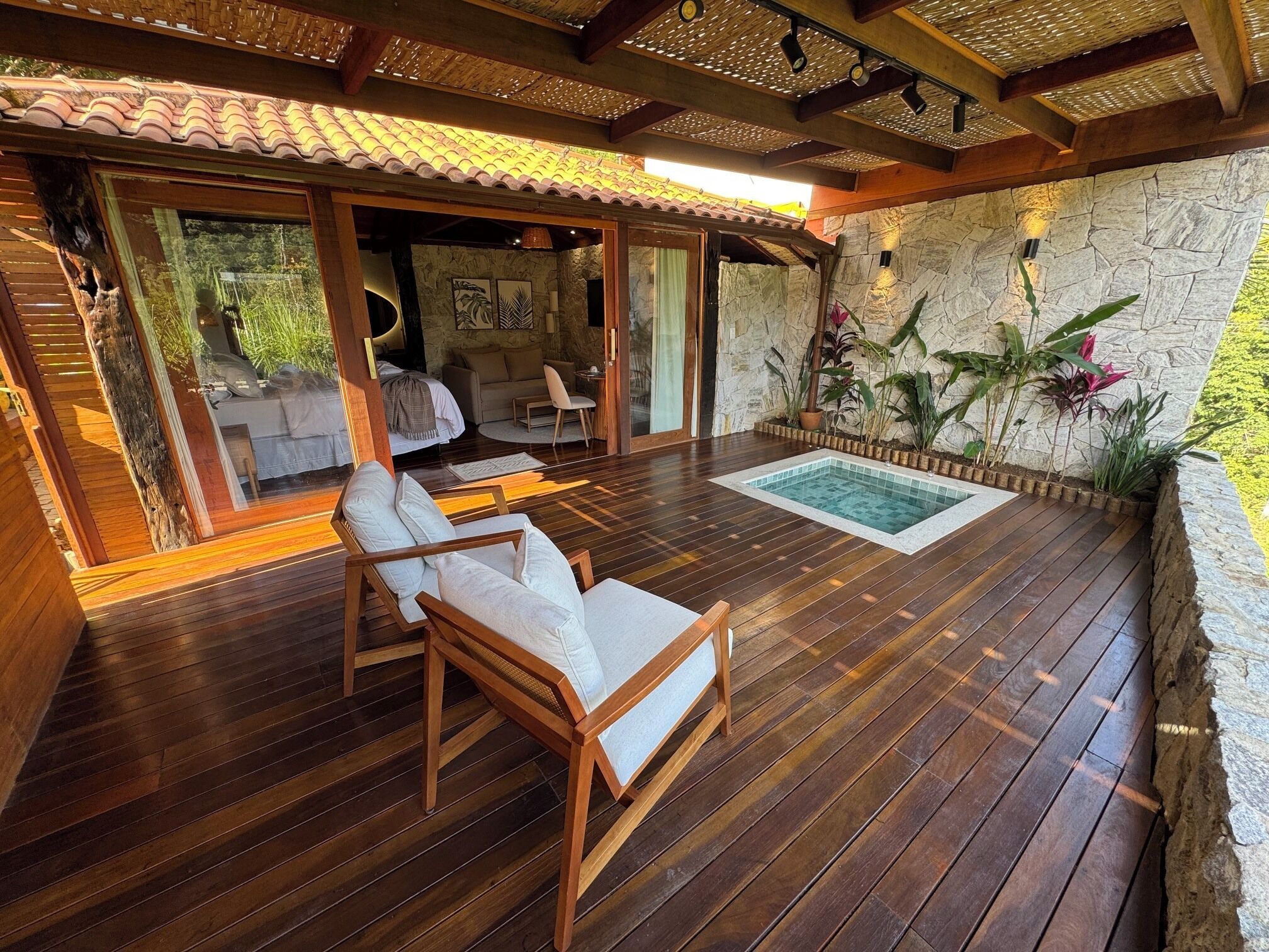 A wooden deck with a pool, a sofa, and a chair.