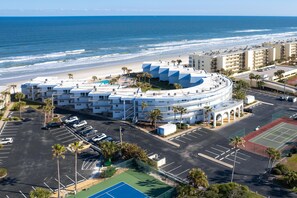 A coastal hotel with a circular building, parking, and a tennis court. - Sandpiper 220 - Remodeled Beachfront Condo with Beach Gear (St. Augustine)