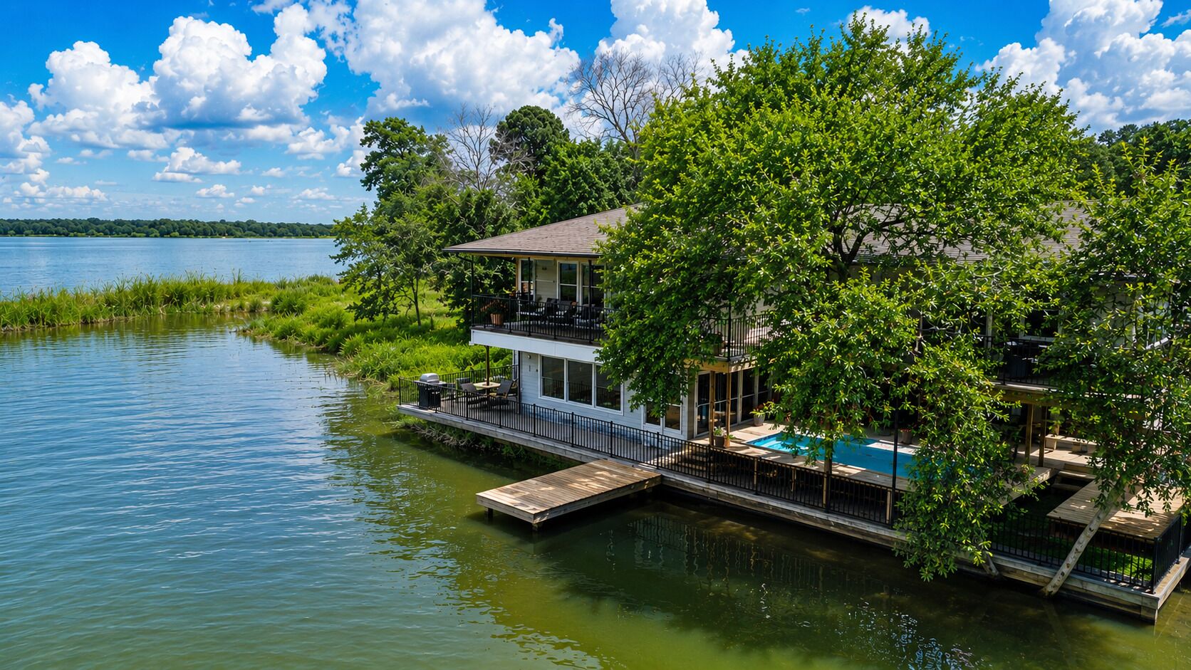 Une maison au bord du lac, dotée d’un quai, d’une piscine et d’un balcon à l’étage.