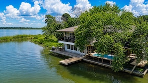 A lakeside house with a dock, a pool, and a second-story balcony.